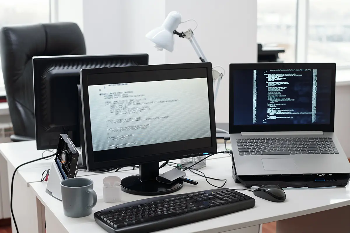 Decoded data on computer and laptop screens standing on workplace of programmer